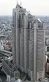 Aerial view of a beige high-rise lined with rows of windows; the building is composed of three adjoined towers of differing heights