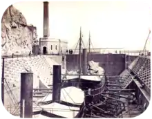 photographie de deux navires à vapeur en cale sèche avec un bâtiment abritant le moteur pour faire fonctionner les portes de l'écluse en arrière-plan