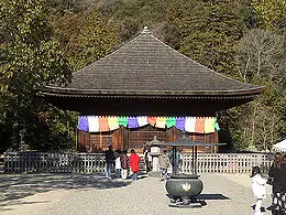 Un bâtiment en bois avec toit en forme de pyramide. Des drapeaux colorés sont suspendus autour des murs extérieurs.