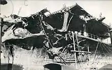 Photo en noir et blanc de la structure d'un porte-avions tordue et en partie démolie.