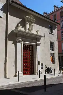 Immeuble avec un portique et une grande porte rouge.