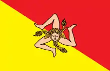 Drapeau avec en son centre un triskèle couleur chair, avec une Gorgone et des épis. Le fond du drapeau est rouge orangé au-dessus d'une diagonale descendente et jaune en dessous.
