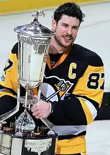 Photographie couleur de Sidney Crosby portant le maillot des Penguins de Pittsburgh et le « C » pour capitaine.