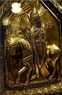 Saint Maurice représenté en soldat romain (casque, cotte de mailles, écu crucifère), décor en argent naturel et dorure sur un côté de la châsse des enfants de saint Sigismond, trésor de l'abbaye d'Agaune.