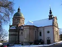 Vue en couleur d'un édifice religieux au toit recouvert de neige sur fond de ciel bleu.