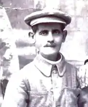 Photo noir et blanc d'un homme en buste, moustachu, avec casquette