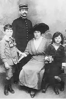 un homme en habit de militaire, avec képi; devant lui, sa femme assise et deux enfants