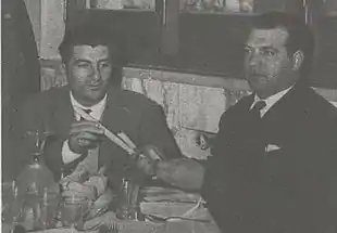 Image en noir et blanc de deux hommes attablés.