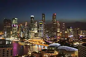 Grattes-ciel de nuit avec la rivière Singapour au pied des immeubles.