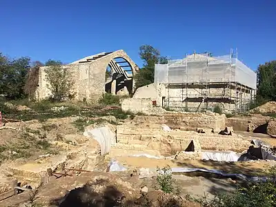 Vue sur le site en cours de fouille et en second plan deux bâtiments d'une verrerie du XVIIIe siècle.