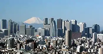 Vue aérienne d'une ville, de nombreux bâtiments de faible hauteur à l'avant-plan avec de nombreux immeubles de grande hauteur dans le fond. Le sommet d'une montagne couverte de neige peut être vu dans la distance.