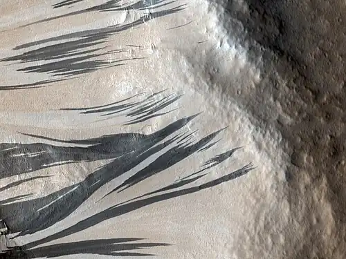 Traînées noires photographiées le 3 décembre 2006 par l'instrument HiRISE de MRO dans la région d'Acheron Fossae, par 37,3° N et 229,1° E. On observe nettement sur cette image l'éclaircissement progressif de ces traînées, qui deviennent plus claires que la surface environnante. La nature exacte des phénomènes en cause n'est pas connue.