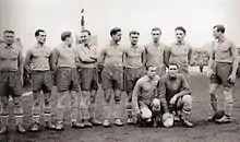 Photographie en noir et blanc de joueurs de football, alignés, vus de trois-quarts.