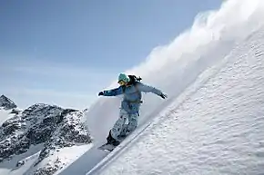 Snowboarder habillé d'une combinaison de ski bleue en train de glisser sur la neige.