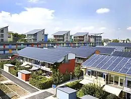 Plusieurs bâtiments colorés avec des toits entièrement recouverts de panneaux solaires.