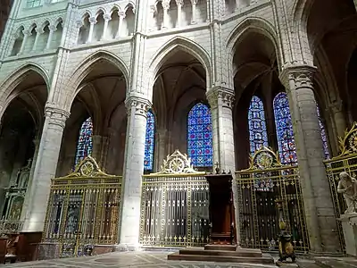 Arcades du chœur, à colonnes soissonaises et grilles en fer forgé, avec la cathèdre de l’évêque.