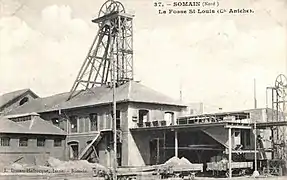 Carte postale ancienne en noir et blanc de la fosse Saint-Louis des mines d'Aniche à Somain, avec son chevalement métallique et ses bâtiments divers. Des wagons sont également visibles.