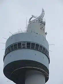Photographie en couleurs représentant le haut d’une tour radar en contre-plongée.