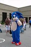 Cosplayeur déguisé en hérisson bleu anthropomorphe.