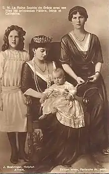Photographie en noir et blanc d'une femme assise portant un diadème, entourée de deux adolescentes et tenant dans ses bras un bébé.