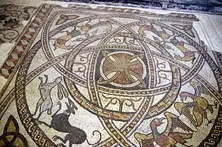 Mosaïque romane dans le chœur de l'église. Un chien poursuivant un lièvre, deux aigles, deux paires de félins les queux entrelacées et au centre une rosace géométrique.