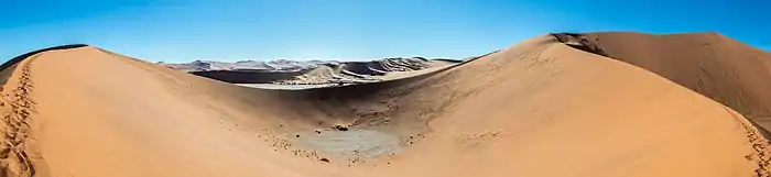 Deux montagnes de sable entourent une petite étendue d'eau à secc.