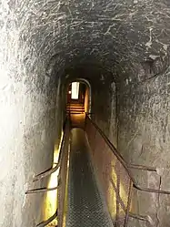 L'entrée du souterrain, avec un pont métallique au-dessus d'une fosse défensive