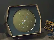 Vieil écran d'ordinateur des années 1960 allumé, affichant quelques points lumineux de couleur blanche.