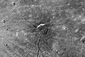 Photographie en noir et blanc d'un large cratère d'où partent des stries.