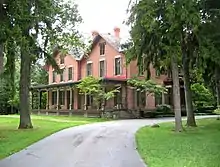 Photographie d'une grande maison de briques entourée par des arbres