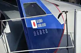 Peints en blanc sur le bleu du cockpit, un drapeau japonais et l'inscription « Kojiro Shiraishi » en caractères latins, puis japonais.