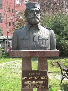 Dans un jardin public, un buste de Draža Mihailović en uniforme.