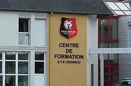 Photographie du logo du Stade rennais et de l'inscription « Centre de formation E.T.P. Odorico ».