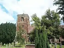 photographie couleurs : une église en briques, dans les arbres, entourée de tombesL'église St-Eata où officiait Algernon Kingsford, à Atcham.