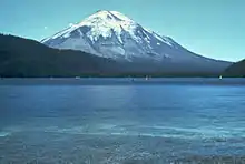 Photographie couleur d'un lac, avec une montagne au sommet enneigé en arrière plan.