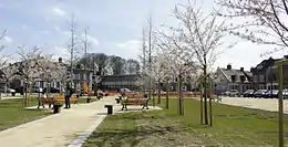 Un square traversé par des allées de gravier bordées d'arbres en fleur.