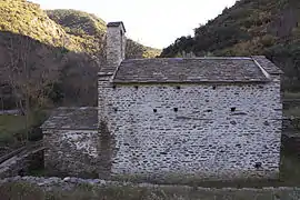 Mur aveugle en pierres surmonté d'un toit.