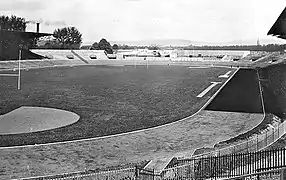 Vue d'un stade vélodrome dont la piste est partiellement couverte par l'ombre du toit d'une tribune.