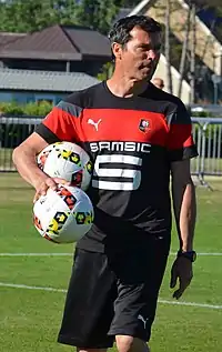 Michel Audrain sous le maillot du Stade rennais, portant deux ballons sous le soleil de Dinard en juillet 2016.