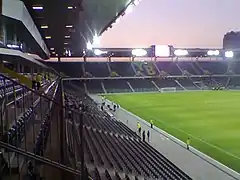 Vue d'un stade de football depuis les tribunes à la tombée de la nuit, les sièges forment les lettres « YB »