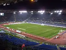 Photo d'un grand stade éclairé de nuit avec peu de spectateurs.