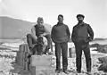 Trois hommes et un chien posant pour une photographie.