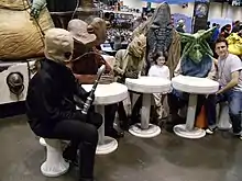 Plusieurs personnes déguisés en extraterrestre autour d'une table.