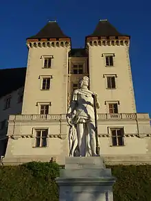 Photographie en couleurs d'une statue devant un château.