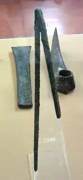 Au premier plan un outil avec 2 branches droites, derrière une sorte de spatule à gauche et une sorte de corne à droite.