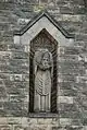 La statue de saint Denis dans une niche du clocher.