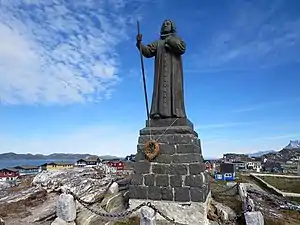 Statue avec des maisons de Nuuk en arrière-plan.