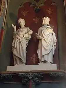 Statues blanches représentant un homme dont les épaules sont percées par des clous et un autre homme couronné et portant une couronne d'épines ainsi qu'un sceptre.