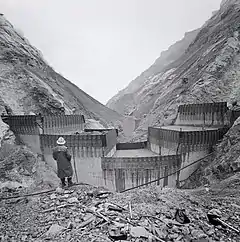 Photographie en noir et blanc de la construction d'un barrage-voûte en béton.