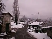 Maison et dépendance le long d'une route sous la neige.